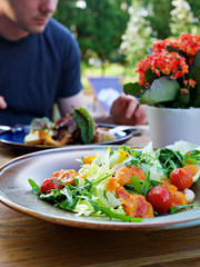 Fresh Shrimps, Mango salad with lettuce green mix, cherry tomatoes, herbs and olive oil, lemon mango dressing. healthy food on wooden table with blurry background in the restaurant