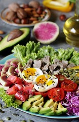 keto diet buddha bowl- salmon, avocado, boiled beef, watermelon radish, egg, salad greens, tomatoes. a bowl of nutrition rich in proteins and fats. sprinkle with oil, season with sunflower seeds
