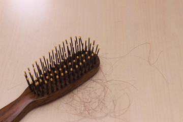 close up top view hair fall at white brown plastick comb at wooden table