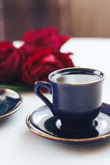 Two coffee mugs on a table decorated with roses