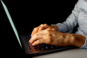 female hands on the laptop keyboard on a dark background