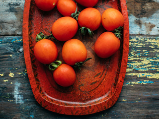 fresh red delicious tomatoes in the heart shape plate on an wooden tabletop.