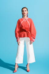 modische frau, die in lebender korallenroter kleidung auf blau aufwirft © LIGHTFIELD STUDIOS