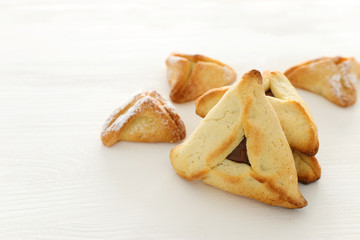 Purim celebration concept (jewish carnival holiday). Traditional hamantaschen cookies over white wooden table.