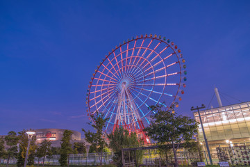 Odaiba illuminated Palette Town Ferris wheel named Daikanransha visible from the central urban area of Tokyo in the summer night sky. Passengers can see the Tokyo Tower.