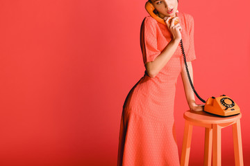 attractive stylish model with vintage rotary phone isolated on living coral.  color of the year 2019 concept