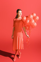 smiling fashionable girl posing with living coral balloons.  color of the year 2019 concept