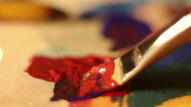 Artist brush mixes paint on the palette. Macro shooting.