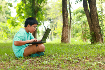 Boys wear eye glasses Pressing a black notebook Sit on the lawn