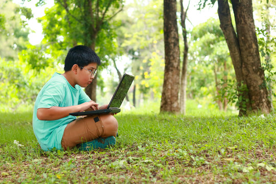 Boys wear eye glasses Pressing a black notebook Sit on the lawn
