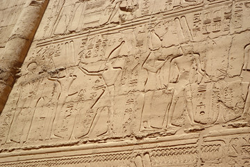 Fototapeta na wymiar Egyptian hieroglyphs, symbols and signs on a stone wall in Karnak temple. Bass-relief.