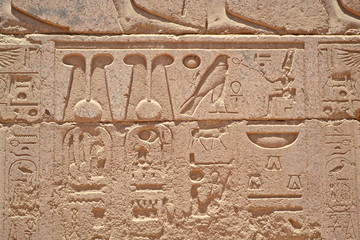 Egyptian hieroglyphs, symbols and signs on a stone wall in Karnak temple. Elements and details of...