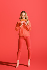 happy woman holding macaroons on living coral.  color of the year 2019 concept