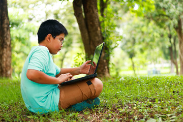 Boys wear eye glasses Pressing a black notebook Sit on the lawn
