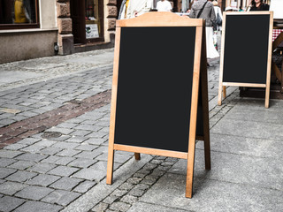 Empty large menu board stand and outdoor cafe, restaurant, blank wooden black board sidewalk restaurants advertising street.