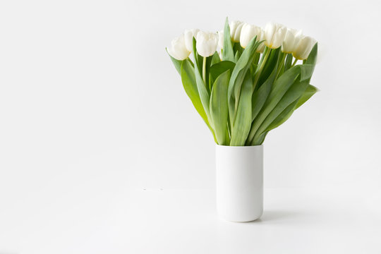 Bouquet of white tulip in vase on white. Space for text.