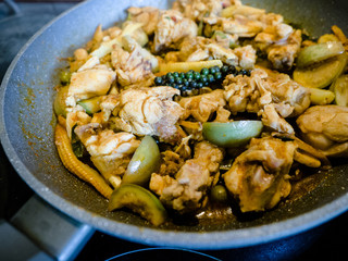 Homemade Thai style Spicy stir-fried chicken meat with pepper and chili, cooking on pan in a kitchen.