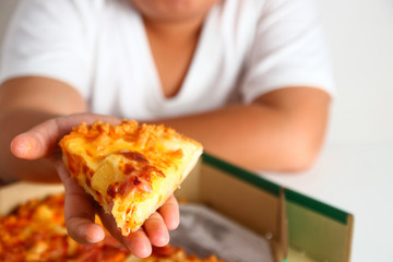 The pizza is in the hands of the fat boy.