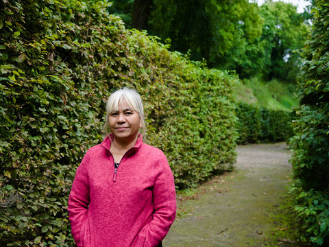 60 Years Old Age Asian Thai Woman Traveling In Europe Old Beautiful City With Garden View On Background For Holiday.