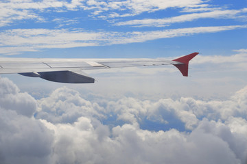 Fototapeta premium View from airplane illumination above the clouds. Wing of plane above cloudy sky in sunny day. Concept of travel, freedom, dreams, transport, eternity, hope.
