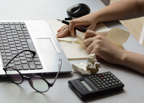 Woman's hands at the office desk are splitting paper in front of the laptop. The accountant makes a mistake in the account. A nervous girl who works from home clears her notes. Student teaches for exa