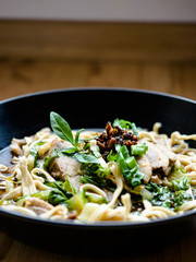Thai Chinese style hot stewed Duck noodles soup served in a black bowl, egg noodles and chili oil on top.