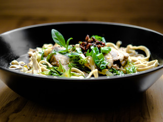 Thai Chinese style hot stewed Duck noodles soup served in a black bowl, egg noodles and chili oil on top.