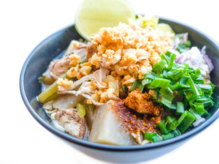 Shred chicken instant noodles with deep fried garlic. chili powder, lemon, spring onion and hot soup with spices in a bowl on white table, Thai noodles food
