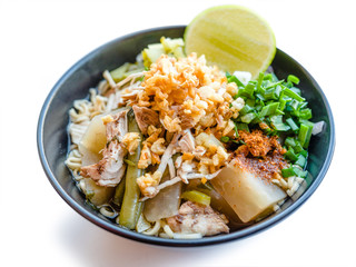 Shred chicken instant noodles with deep fried garlic. chili powder, lemon, spring onion and hot soup with spices in a bowl on white table, Thai noodles food