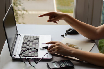 Young woman point the finger at the laptop at the office desk. a female accountant reads documents from a computer. A student shows her colleagues a part of the exam on a computer.