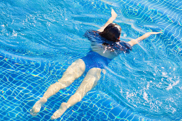 Top view of woman swimming in a pool. Straight body, slim woman. Swim and fitness concept.