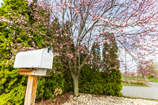 old white mailbox is a vintage style mailbox that is used for long periods of time, resulting in dirt and rust caused by moisture, because the mailbox is installed in front of the house