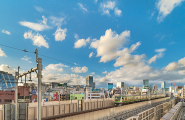 Fototapeta premium kanda station where the trains of the yamanote line pass between the top of the buildings of the district of Chiyoda under the blue sky of Tokyo.