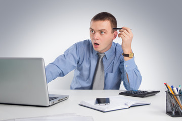 Surprised businessman with laptop computer and documents at office on gray background