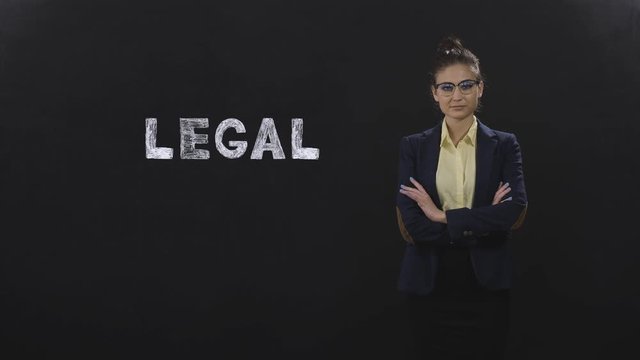 Woman in a formal suit posing on a black background with the word - legal