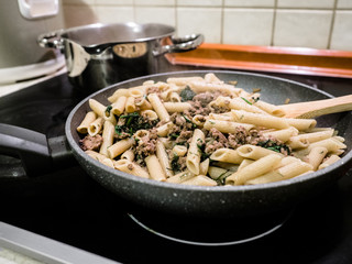 Asian homemade style stir fried Penne Pasta with minced beef and chopped dill. horizontal view from above in a kitchen at home.
