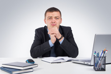 Frustrated young businessman working on laptop computer at office