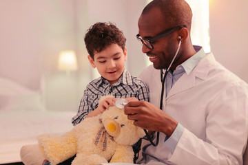 Doctor and a kid inspecting a teddy bear together