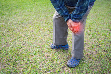 Close-up of senior man suffering from knee ache at his garden. Healthcare Concept.