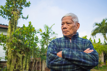 Naklejka na ściany i meble Portrait of elderly man standing in home garden.