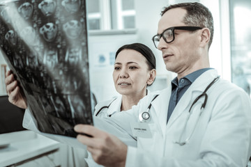 Couple of professional doctors attentively reviewing x-ray photo