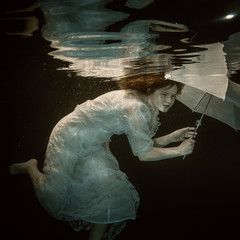Girl in dress with umbrella under water