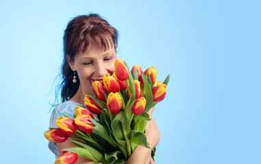 Obraz na płótnie Canvas Attractive woman in blue dress with a bouquet of red and yellow tulips.