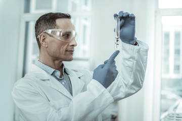 Smiling researcher in clear glasses holding test tube