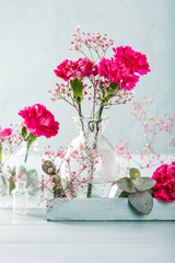 Bouquet of pink carnation in glass vase on light turquoise wooden background. Mothers day, birthday greeting card. Copy space.