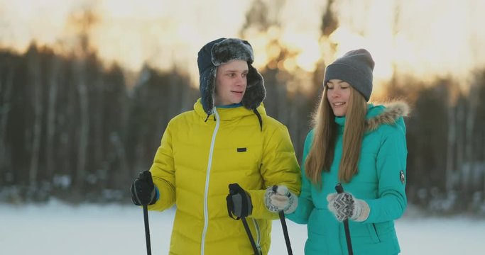 Full length portrait of caring young man helping injured girlfriend during ski walk in winter forest