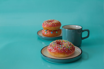 Pink glazed doughnuts with sprinkles on turquoise background