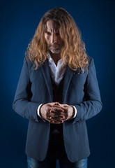 long-haired stylish man in jeans and jacket on a blue background. Studio photography