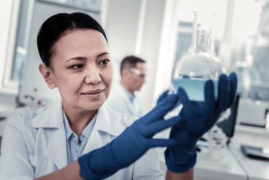 Scientist holding the chemical flask with the liquid