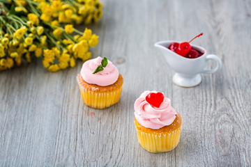 Tasty cupcake on wooden background. Birthday cupcakes on gray wooden background. Cupcakes with heart-shaped jellies. Space for Text.